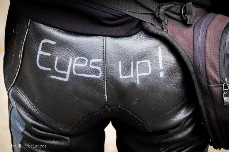 Nahaufnahme der Rückseite einer schwarzen Lederhose mit der Aufschrift 'Eyes up!'